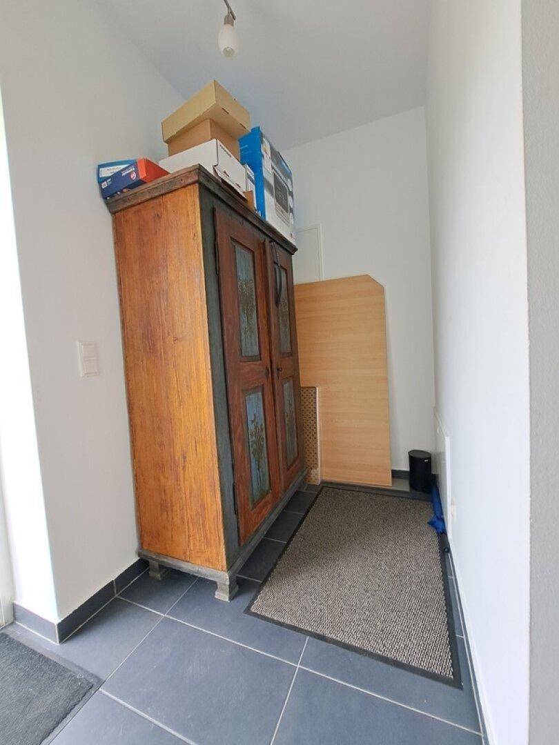 Eingangsbereich mit dunklen Fliesen und einem antiken Schrank, bietet praktischen Stauraum.