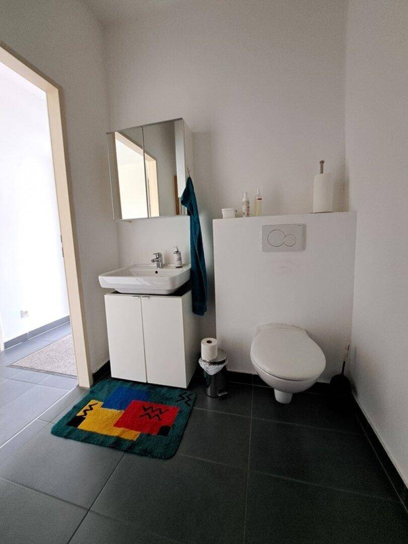 Modernes Gäste-WC mit Waschbecken, Spiegel und wandhängender Toilette.