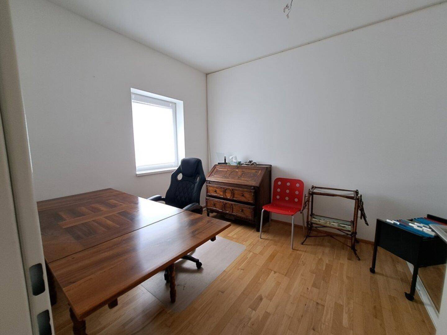 Geräumiges Büro mit großem Holztisch und Schreibtisch, ideal für produktives Arbeiten.