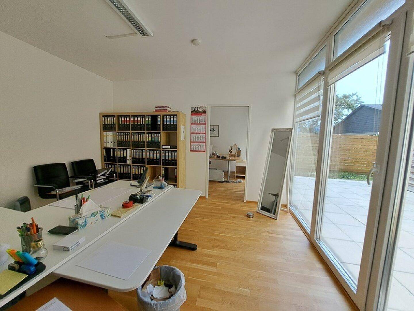 Großes Büro mit mehreren Arbeitsplätzen und breiter Fensterfront zur Terrasse.