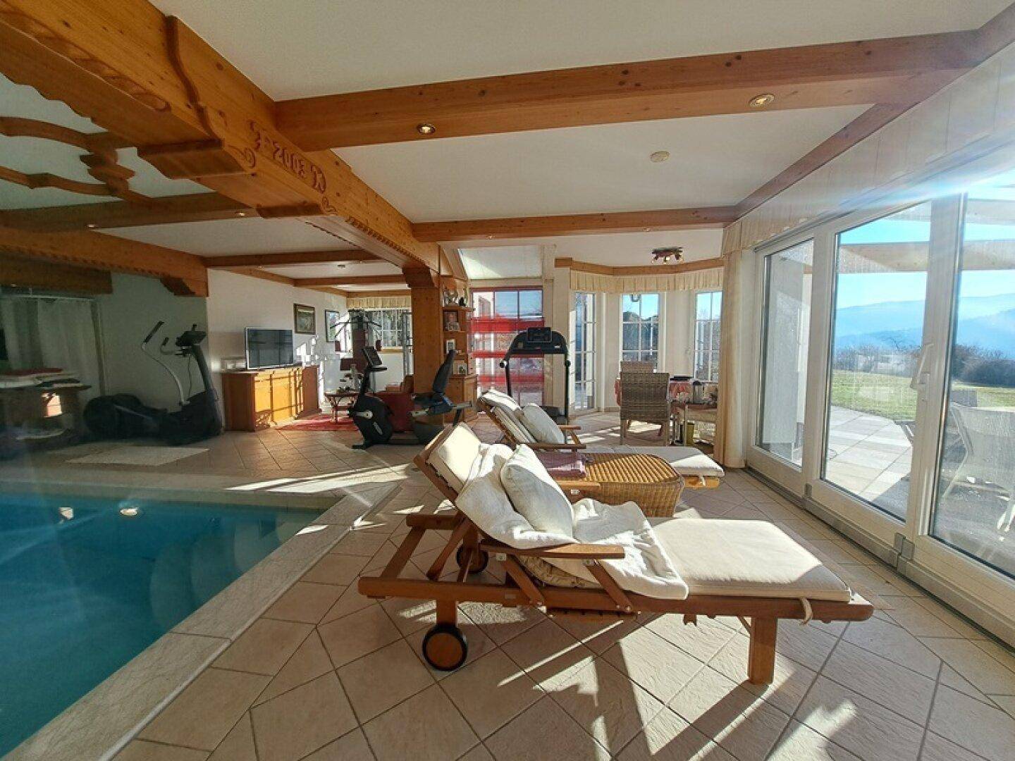 Heller Poolbereich mit Liegestühlen, Fitnessgeräten und Zugang zur Terrasse.