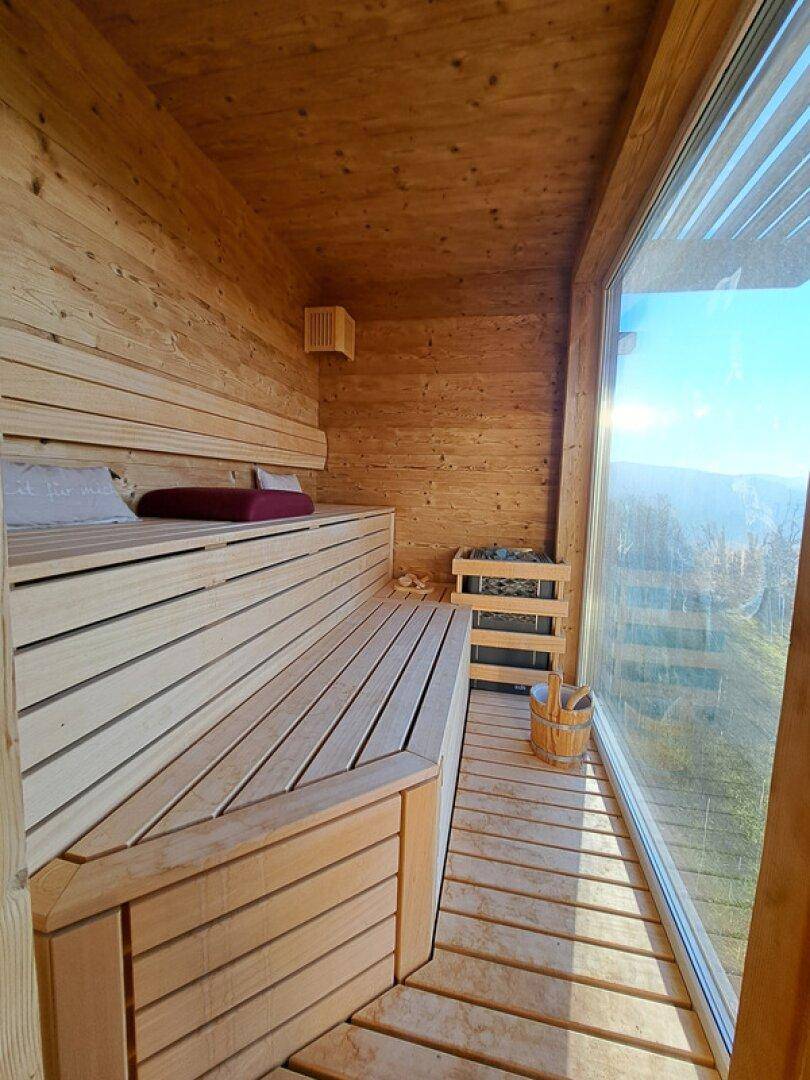 Moderne Sauna mit Holzverkleidung und großem Fenster mit Panoramablick.