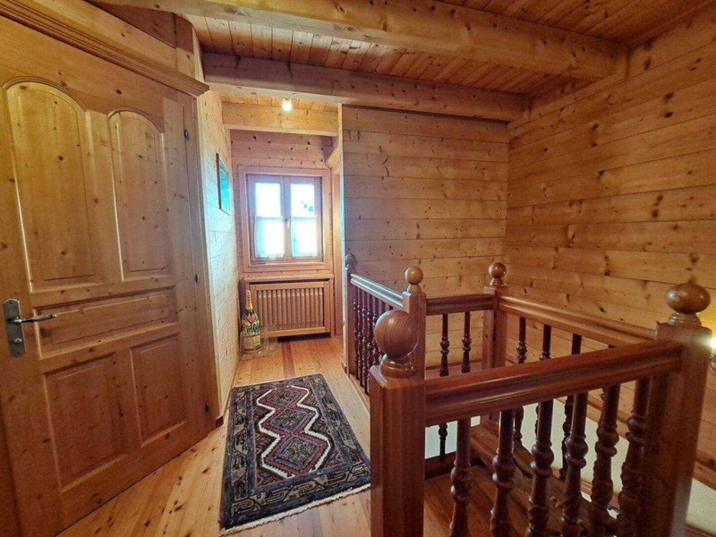 Heller Flur mit Holzboden, Holzwänden und Zugang zu weiteren Räumen.