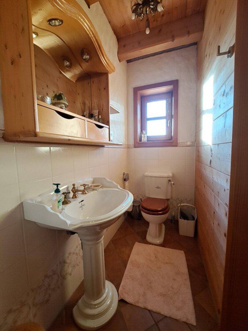 Traditionelles Gäste-WC mit Standwaschbecken, Toilette und Holzverkleidung.