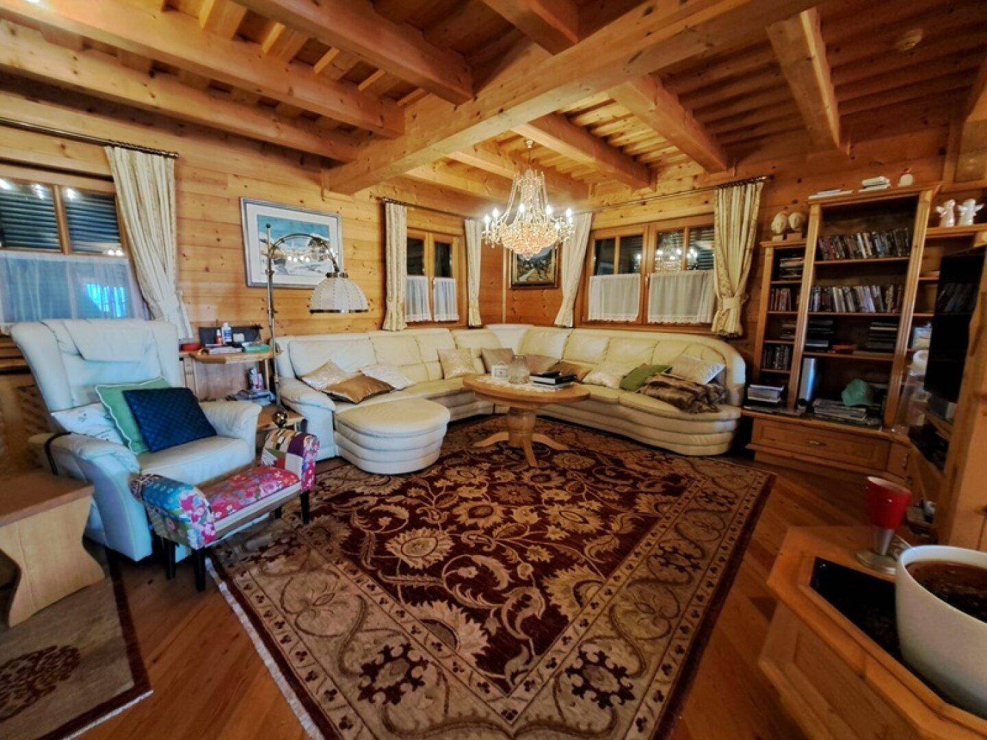 Geräumiges Wohnzimmer mit großer Eckcouch, Holzwänden und Kronleuchter.