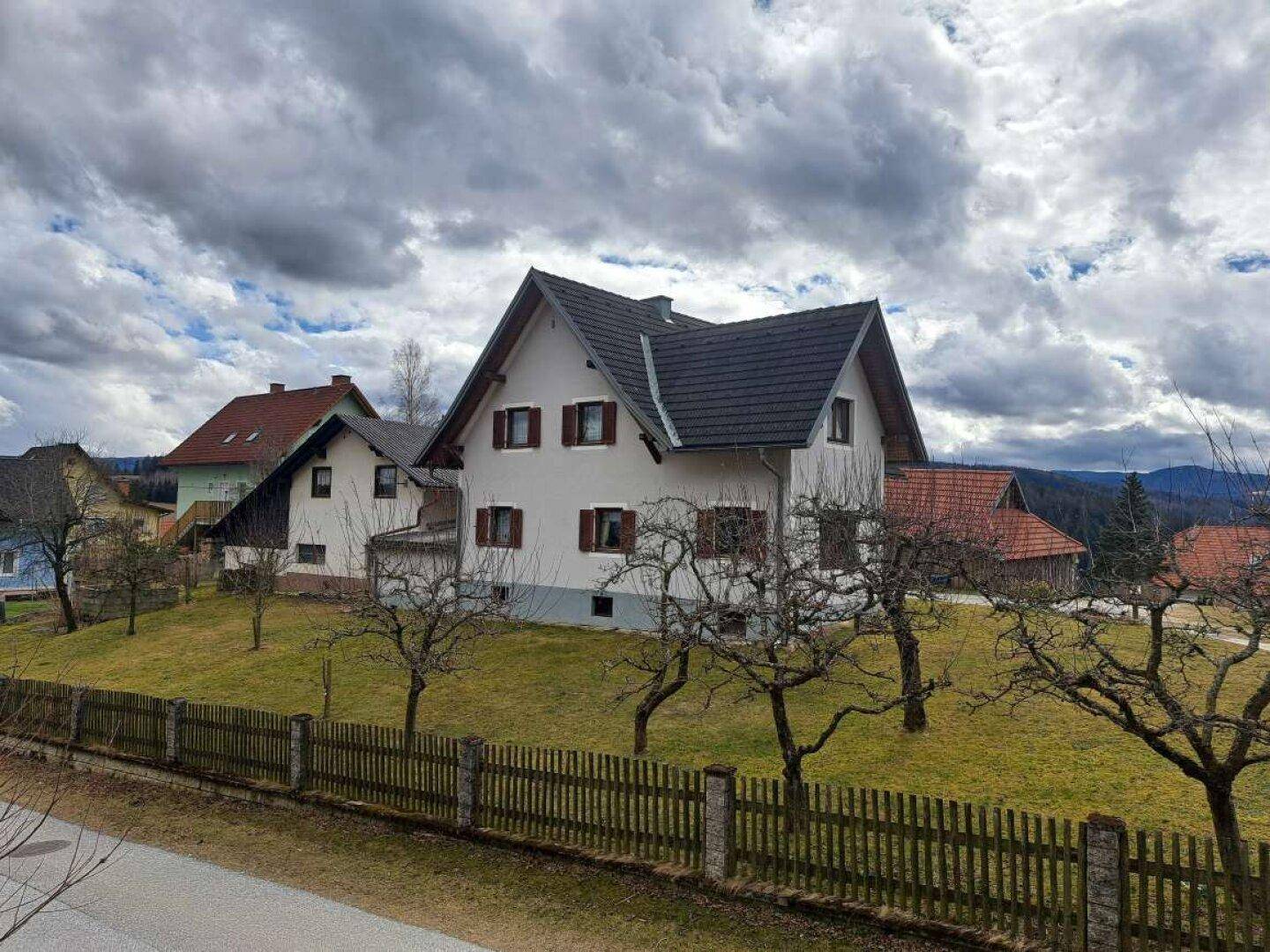 Weitläufiger Blick auf das Haus und die umliegende grüne Landschaft mit bewölktem Himmel.