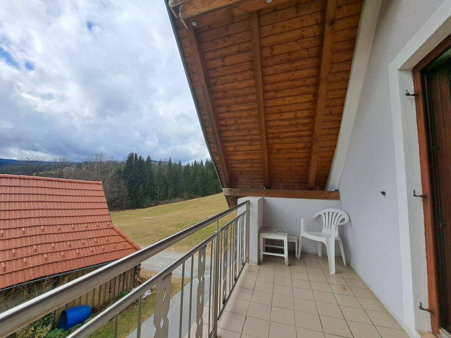 Kleiner Balkon mit Fliesenboden und Metallgeländer, bietet einen weiten Blick ins Grüne.