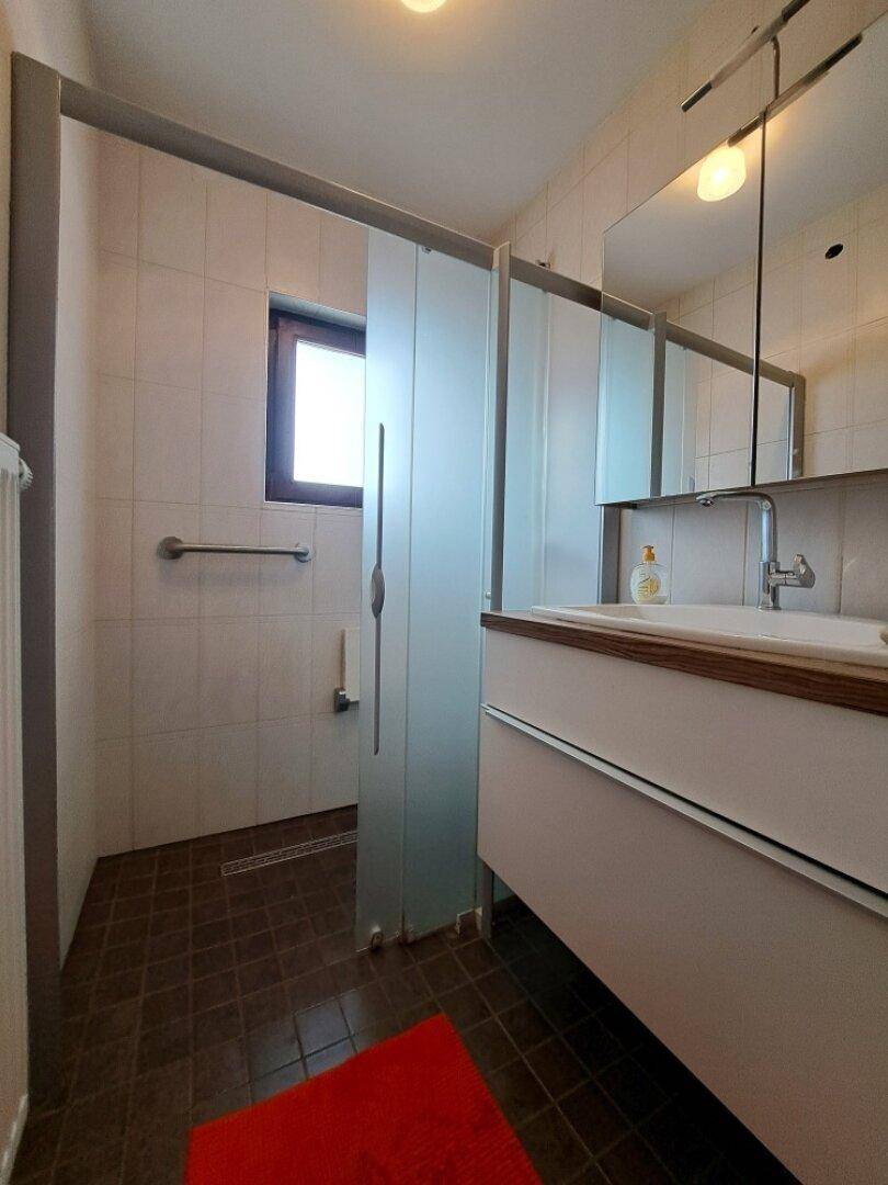 Modernes Badezimmer mit begehbarer Dusche, Waschbecken und einem Fenster für Tageslicht.