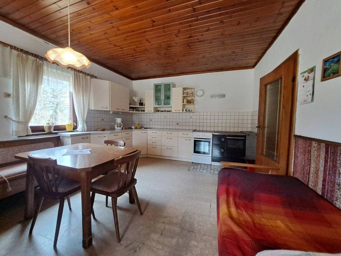 Geräumige Küche mit Holzdecke, Essbereich und einem traditionellen Holzofen.