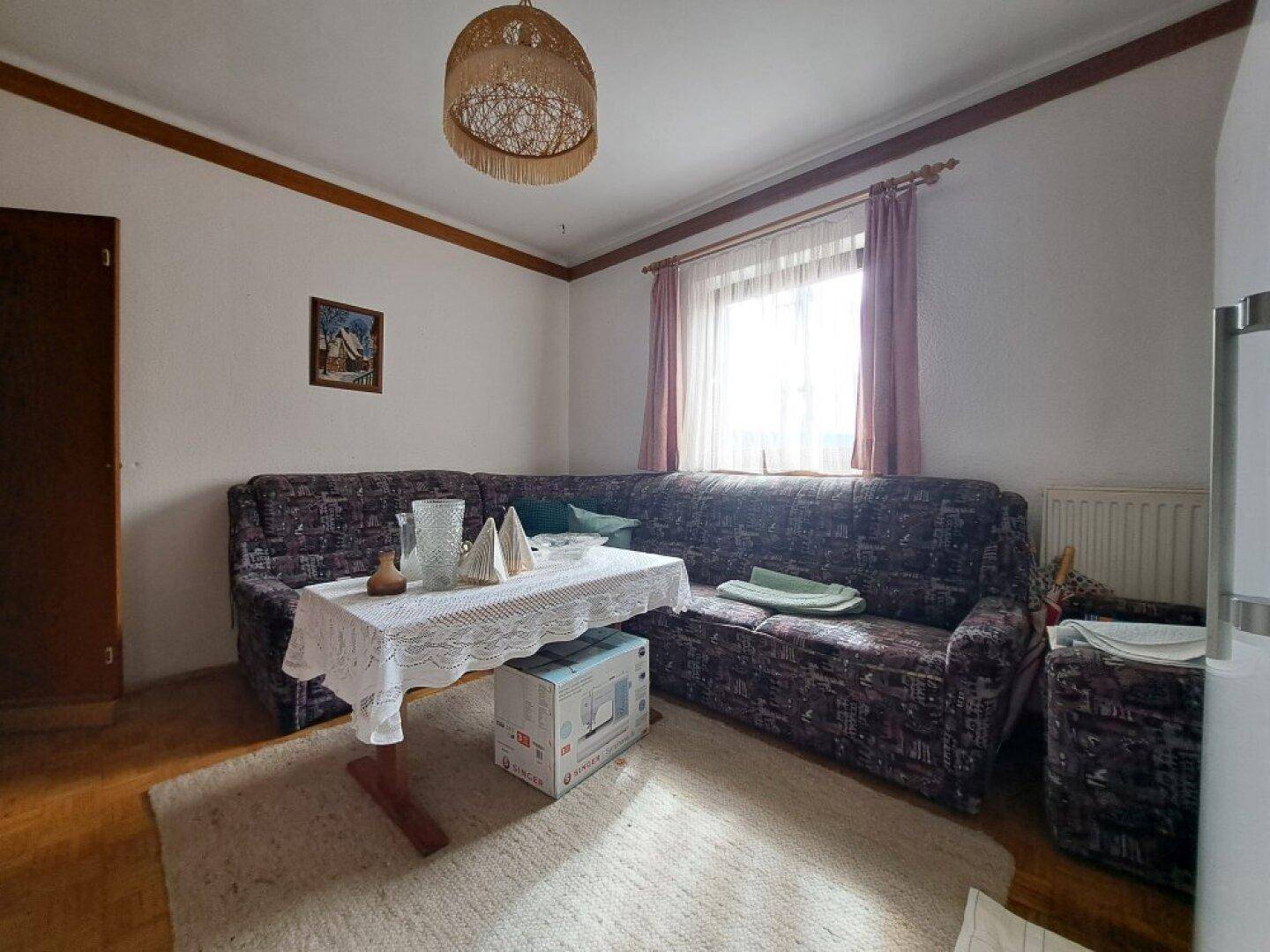 Gemütliches Wohnzimmer mit Sofa, Teppichboden und einem Fenster für natürliches Licht.