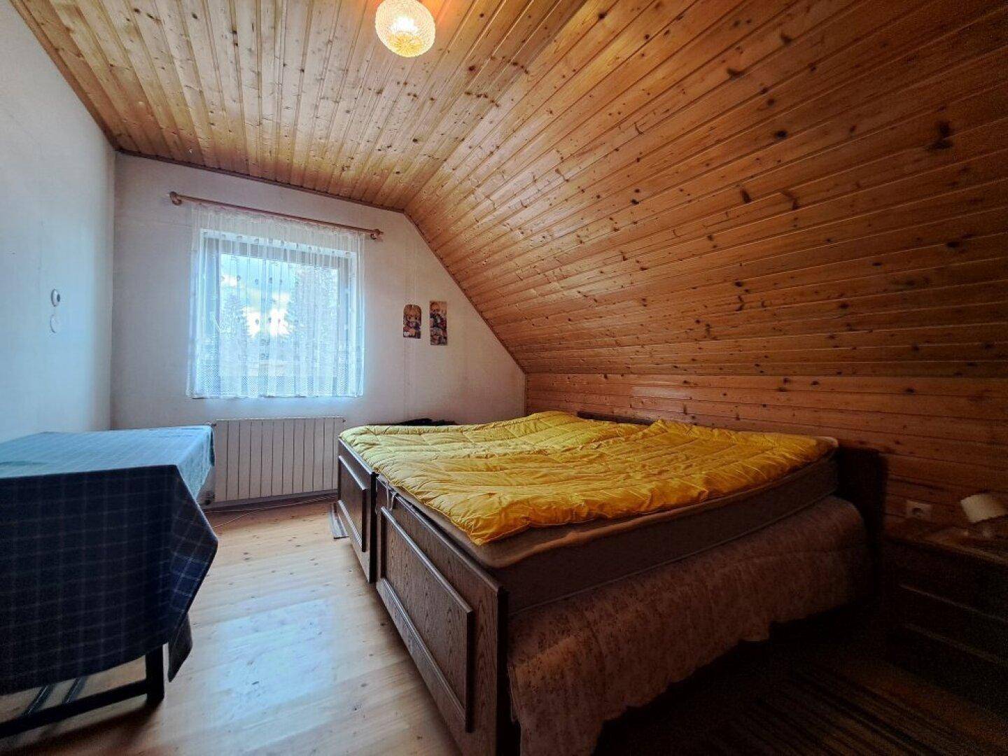 Geräumiges Schlafzimmer mit Holzdecke, Doppelbett und Blick auf die Landschaft.