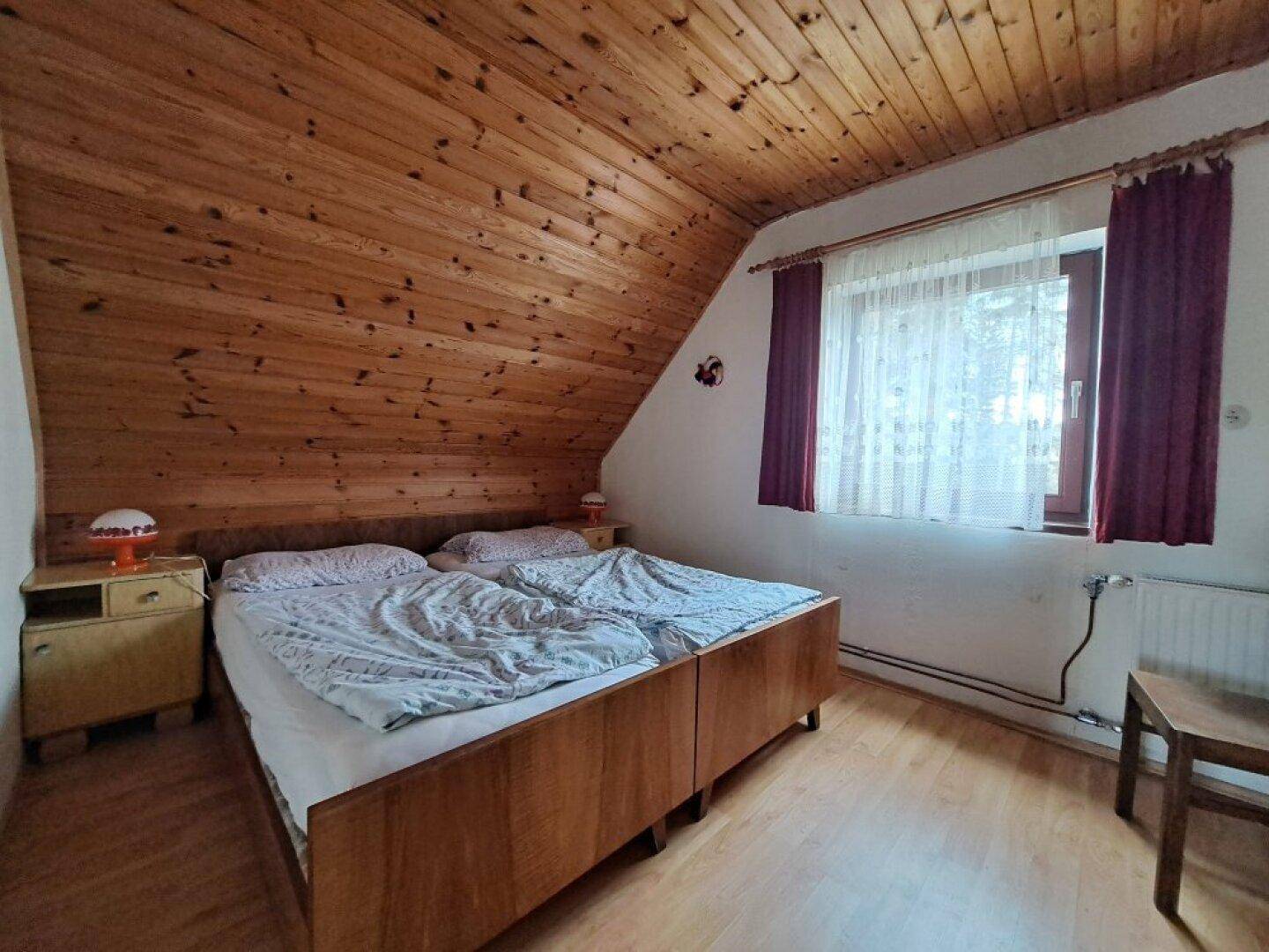 Helles Schlafzimmer mit Holzdecke, zwei Einzelbetten und Holzfußboden.
