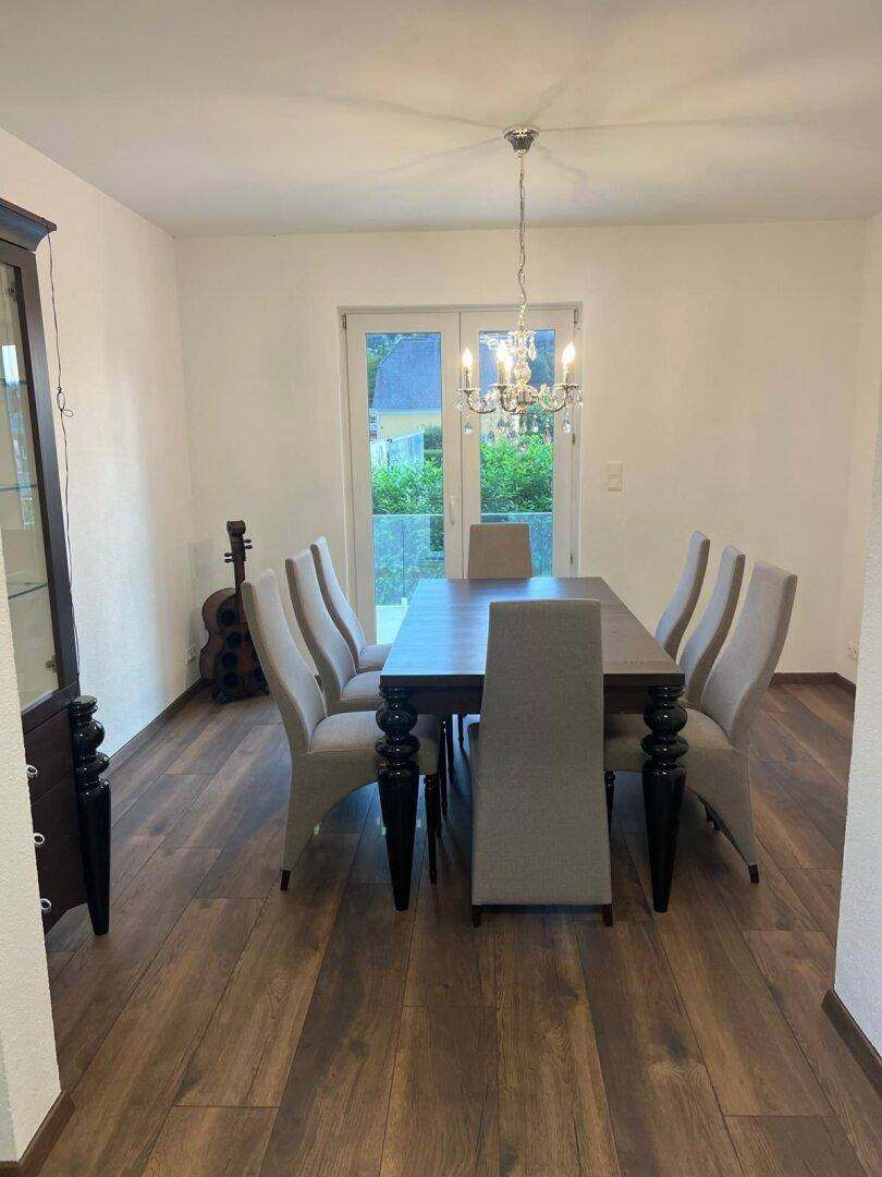 Eleganter Essbereich mit großem Holztisch, bequemen Stühlen und Balkonzugang für frische Luft.