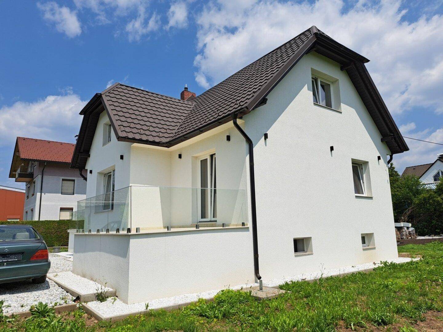 Rückansicht des modernen Einfamilienhauses mit weißer Fassade und Satteldach im Grünen.