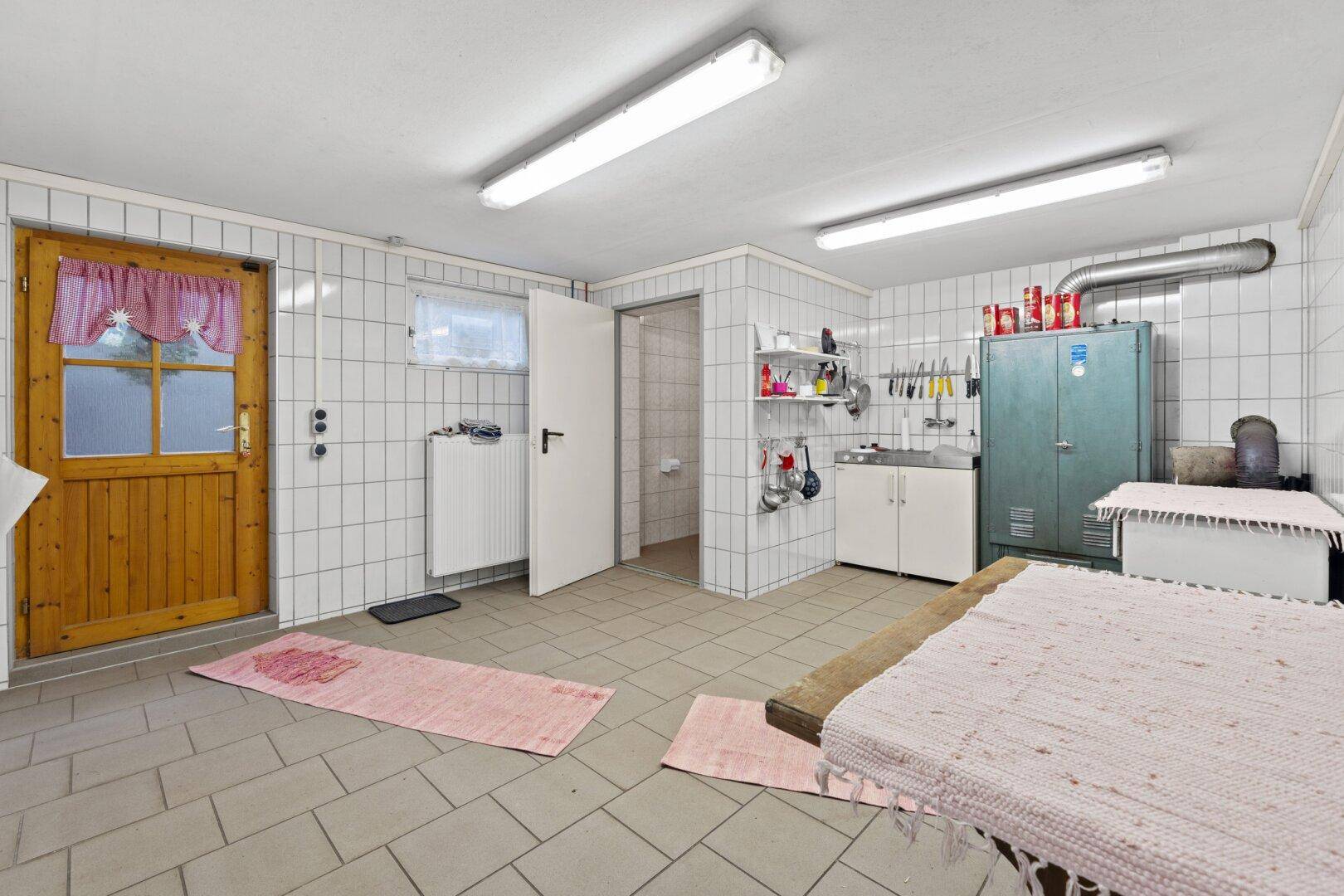 Funktionaler Hauswirtschaftsraum mit Fliesenwänden, Fliesenboden und praktischer Ausstattung.