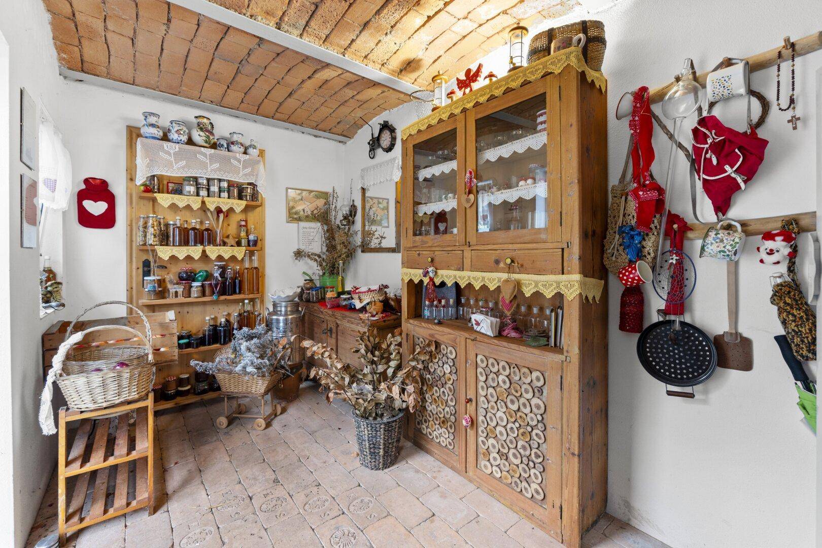 Rustikale Speisekammer mit Holzregalen, Vorräten und einer Ziegeldecke.