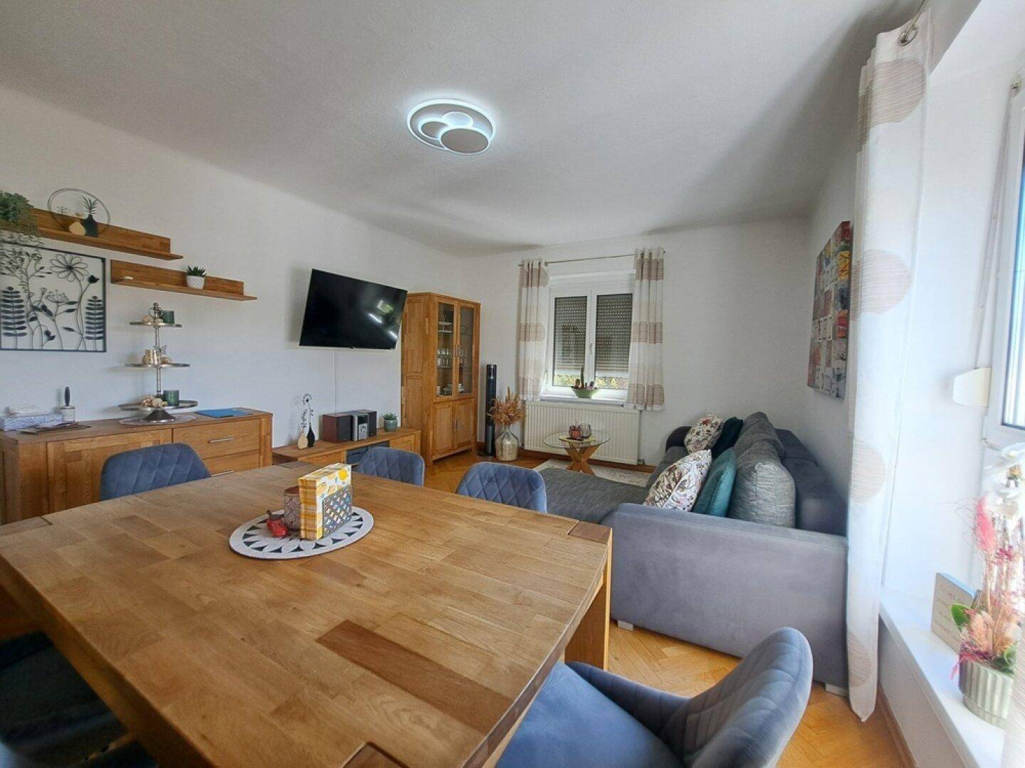 Heller Wohn- und Essbereich mit Holztisch, passenden Möbeln und Parkettboden, ideal für gesellige Stunden.