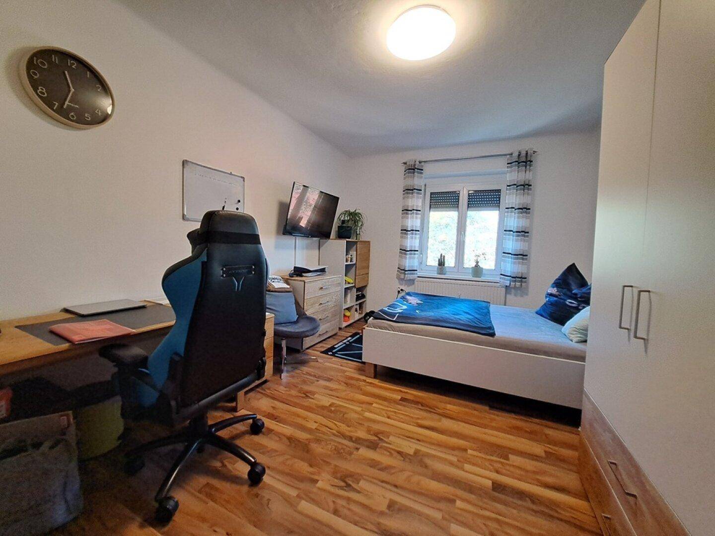 Helles Jugendzimmer mit Schreibtisch, Gaming-Stuhl und Einzelbett, ideal zum Lernen und Entspannen.