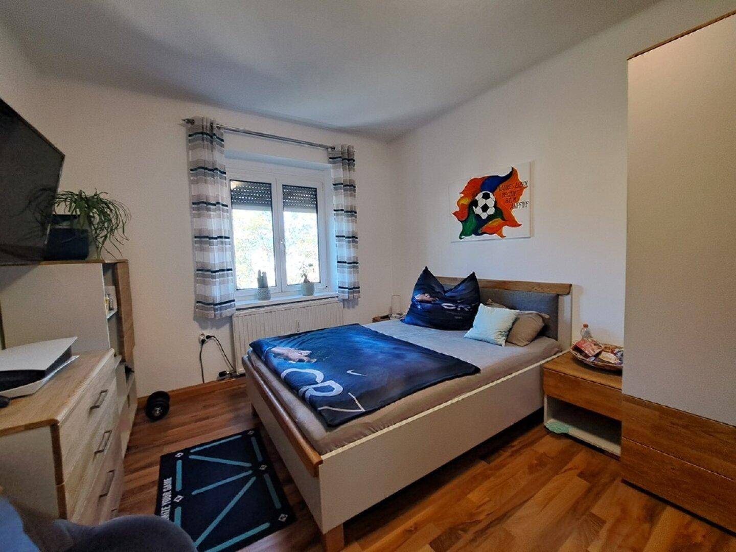 Jugendzimmer mit Einzelbett, Holzmöbeln und einem Fenster, das für natürliches Licht sorgt.