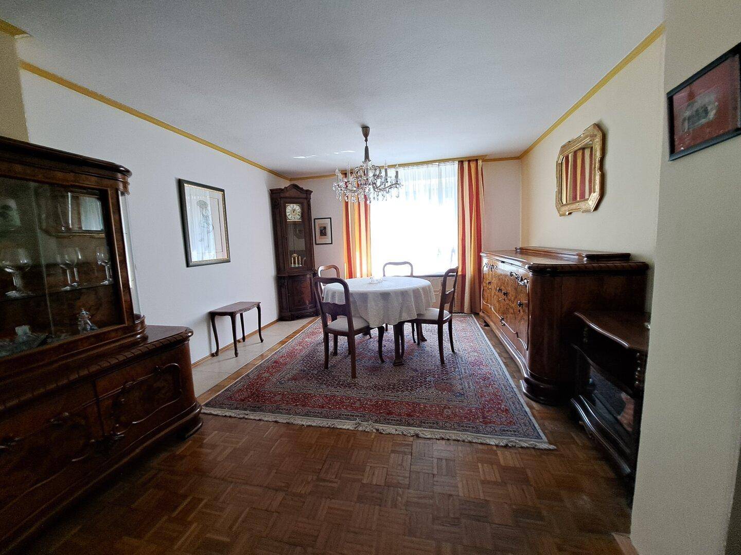 Klassischer Essbereich mit Holzboden, Teppich und antiken Möbeln.