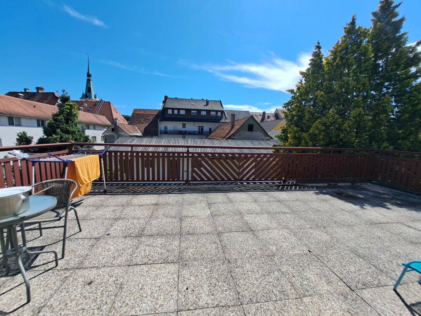 Sonnige Terrasse mit Stadtblick und Wäscheständer unter blauem Himmel.