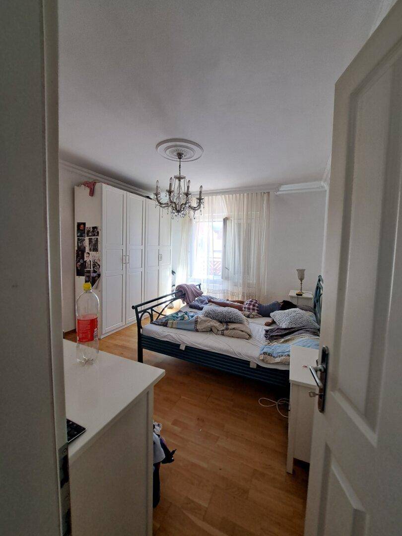 Schlafzimmer mit Holzboden, Kleiderschrank und Kronleuchter.