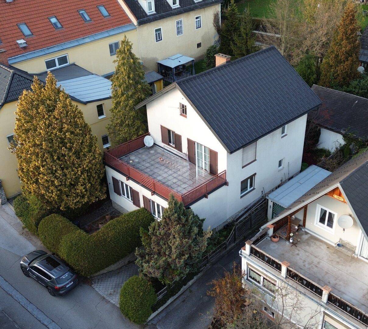 Luftaufnahme eines Wohnhauses mit großer Terrasse und angrenzender Straße.