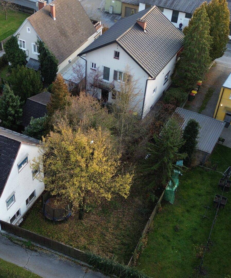 Luftaufnahme des Hinterhofs eines Hauses mit Garten, Bäumen und Trampolin.