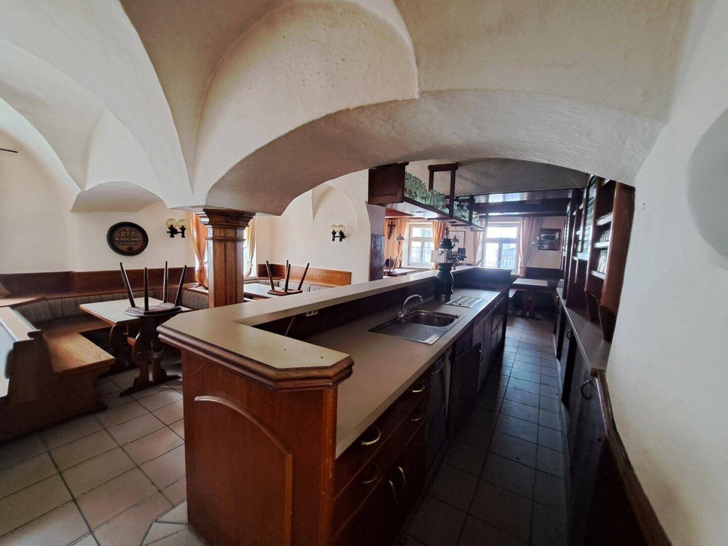 Historischer Gastraum mit gewölbten Decken, einer langen Bar und traditionellen Holzbänken.