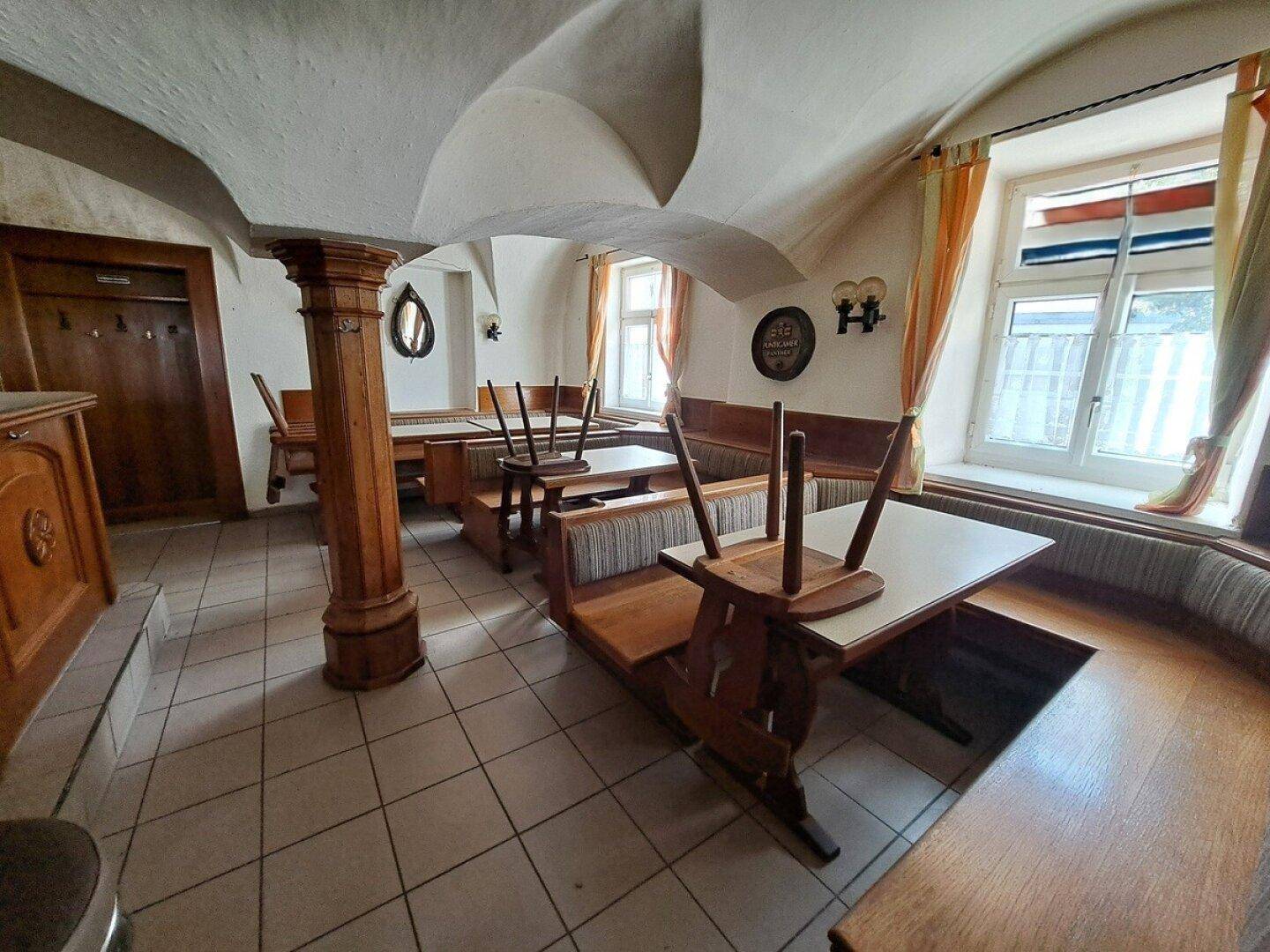 Traditioneller Gastraum mit gewölbten Decken, Holzbänken und gefliestem Boden, der eine rustikale Atmosphäre schafft.