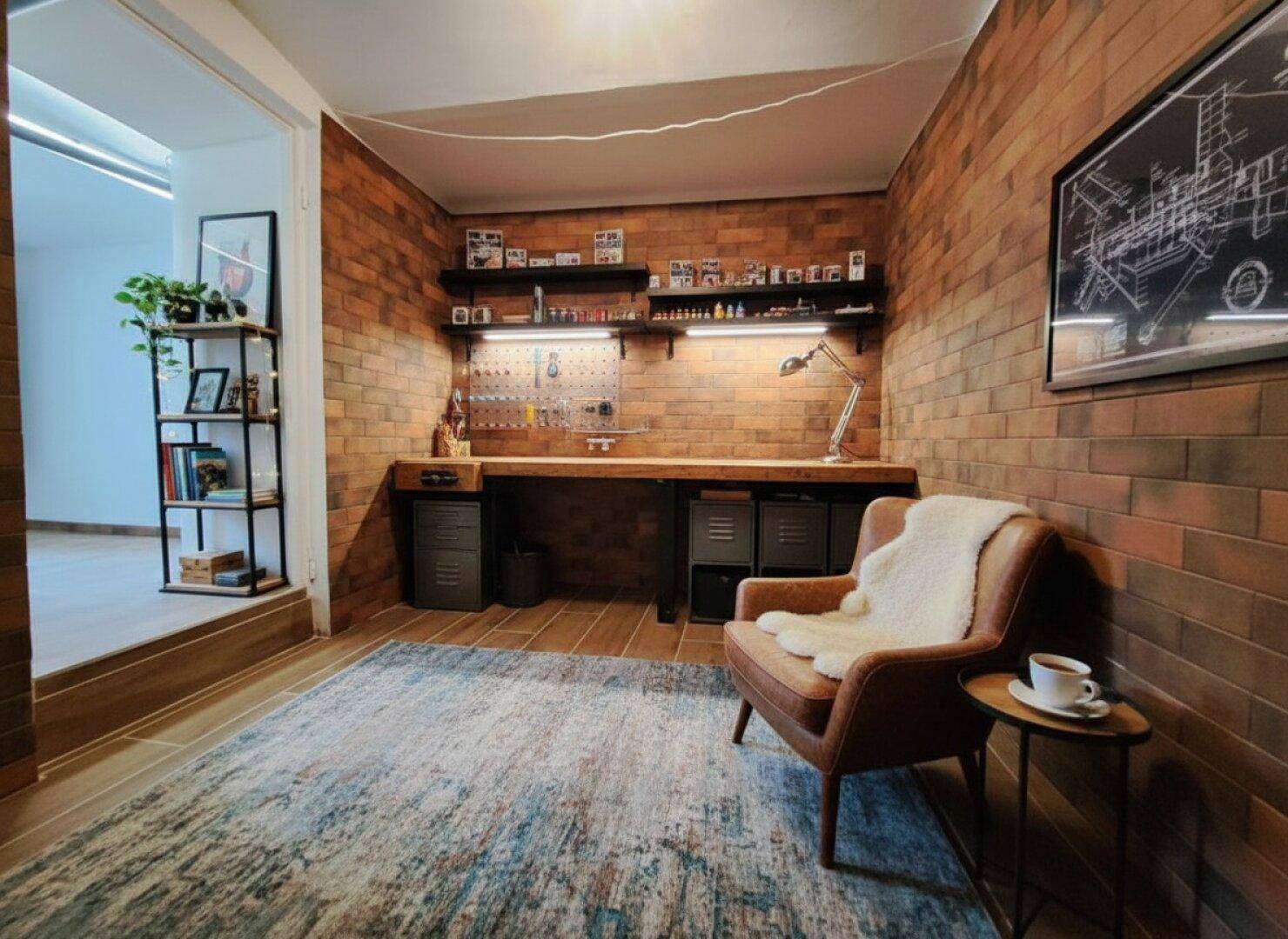 Kreativer Arbeitsbereich mit Ziegelwänden, Schreibtisch und gemütlichem Sessel.