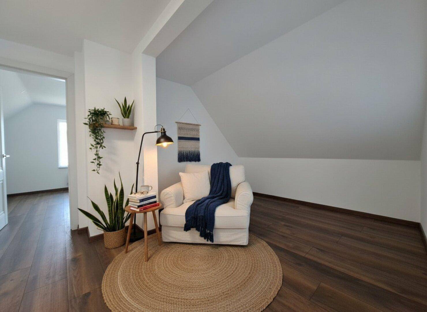 Gemütlicher Lesebereich im Dachgeschoss mit Sessel, Stehlampe und Holzboden.