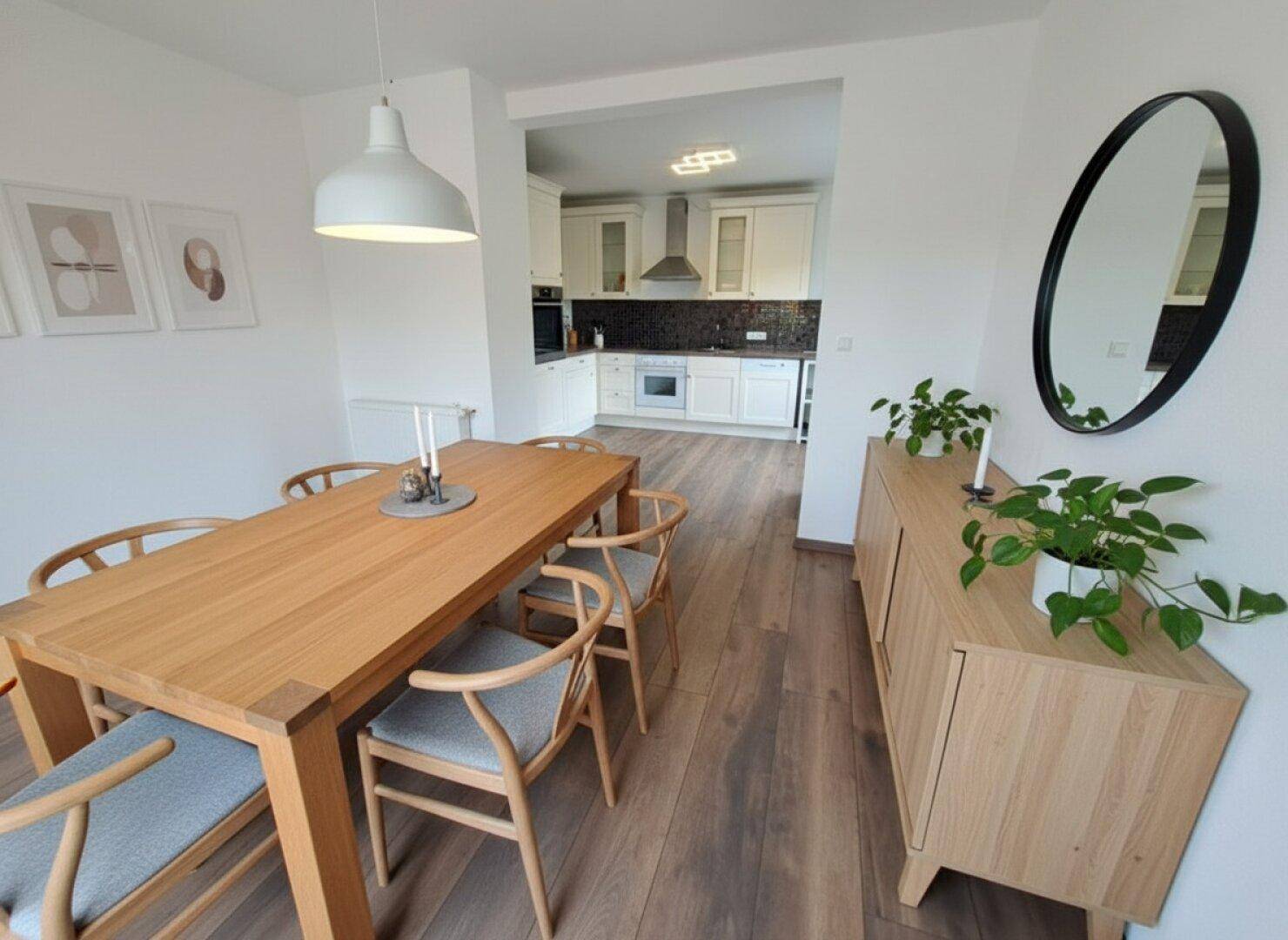 Essbereich mit Holztisch und Stühlen, offen zur modernen Küche, mit dunklem Holzboden.
