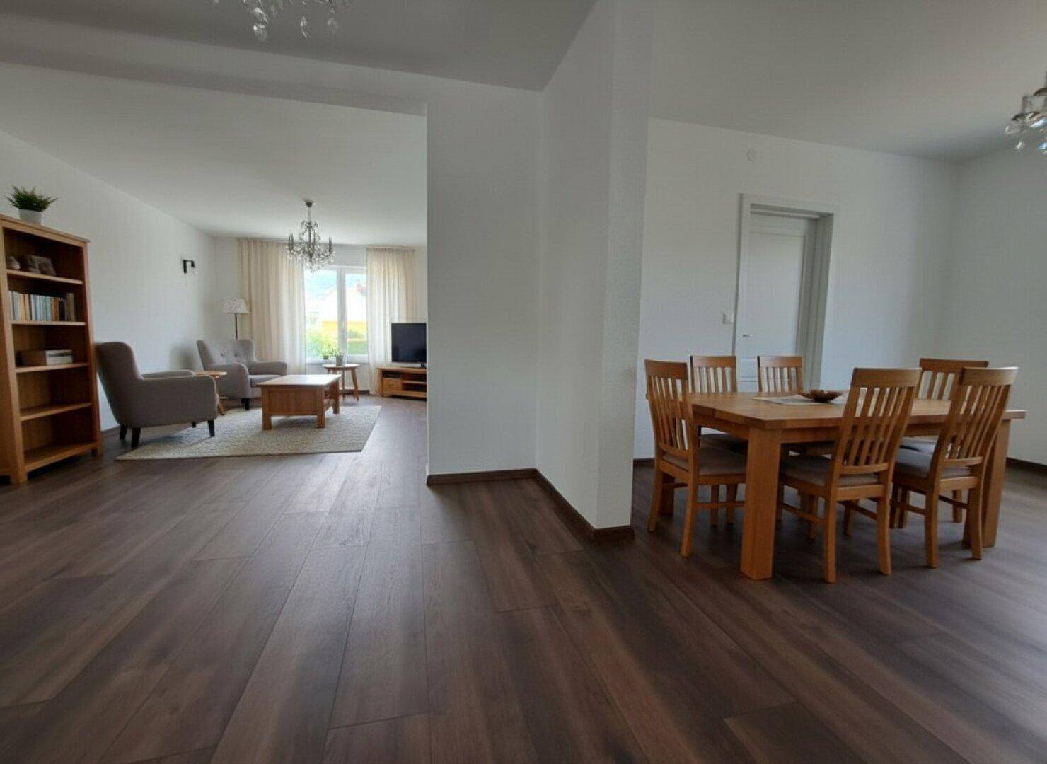 Offener Wohn- und Essbereich mit dunklem Holzboden, Esstisch und Blick ins Wohnzimmer.