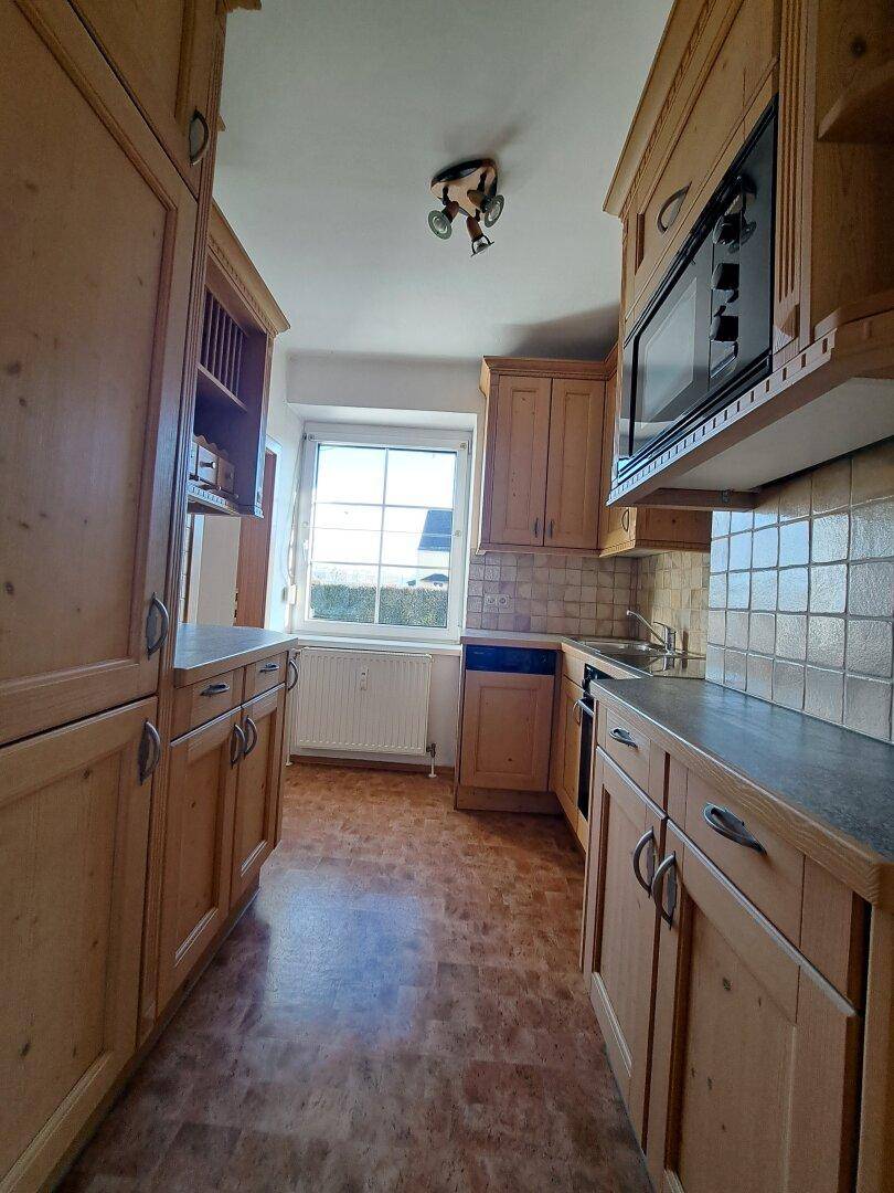 Traditionelle Küche mit Holzschränken, Einbaugeräten und Fenster.