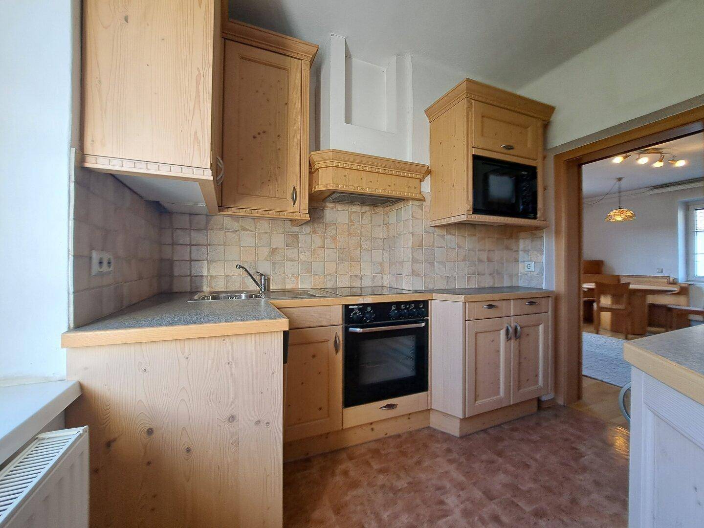 Küche mit Holzfronten, Herd, Backofen und gefliestem Fliesenspiegel.