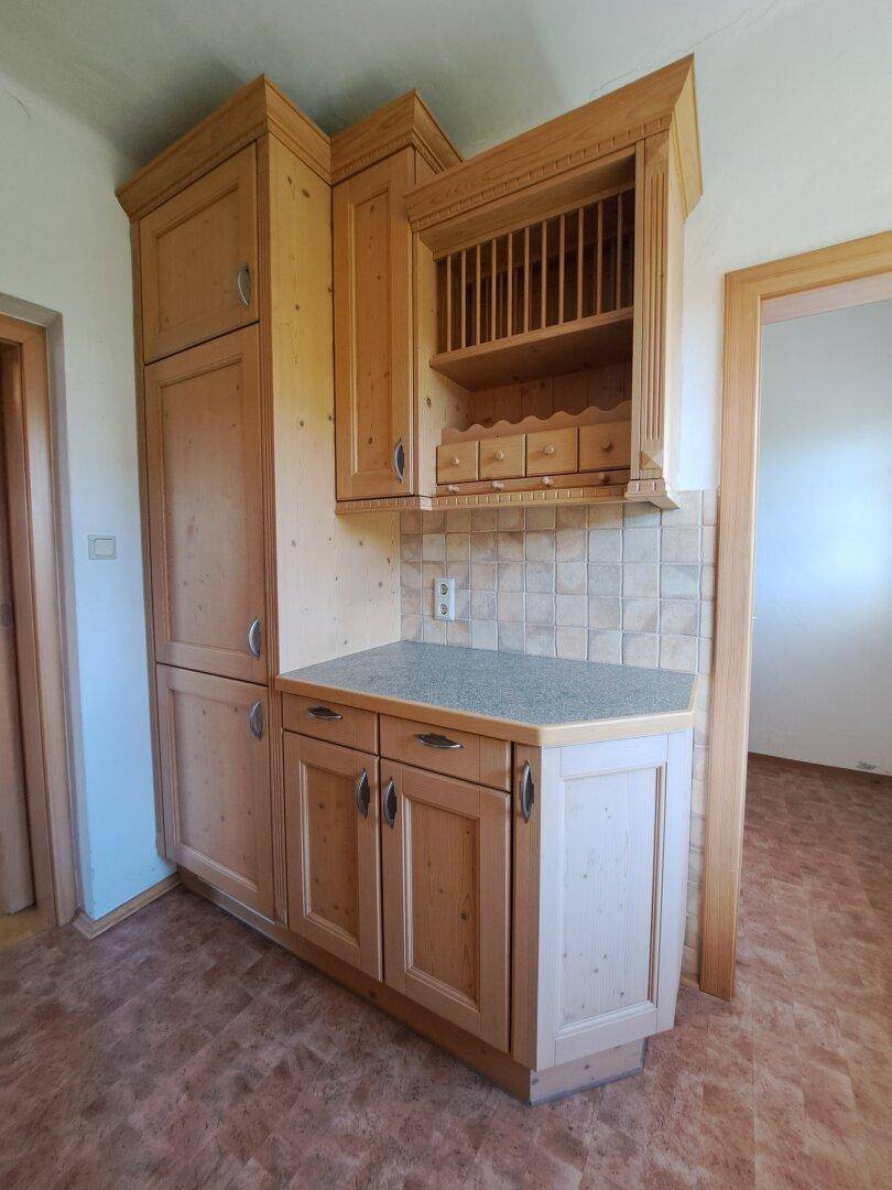 Küche mit Holzschränken, Arbeitsplatte und integriertem Geschirrschrank.