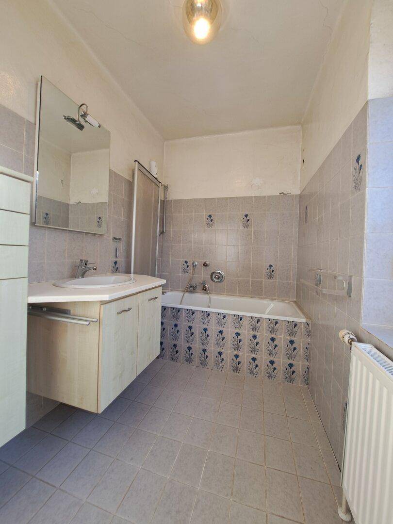Badezimmer im Stil der 80er Jahre mit Badewanne, Waschbecken und Fliesen.