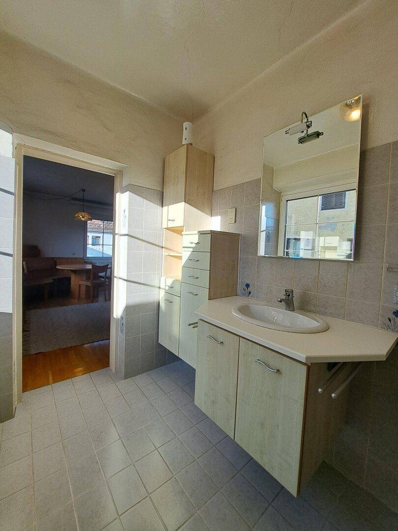 Badezimmer mit Waschbecken, Spiegel und Fenster für natürliches Licht.