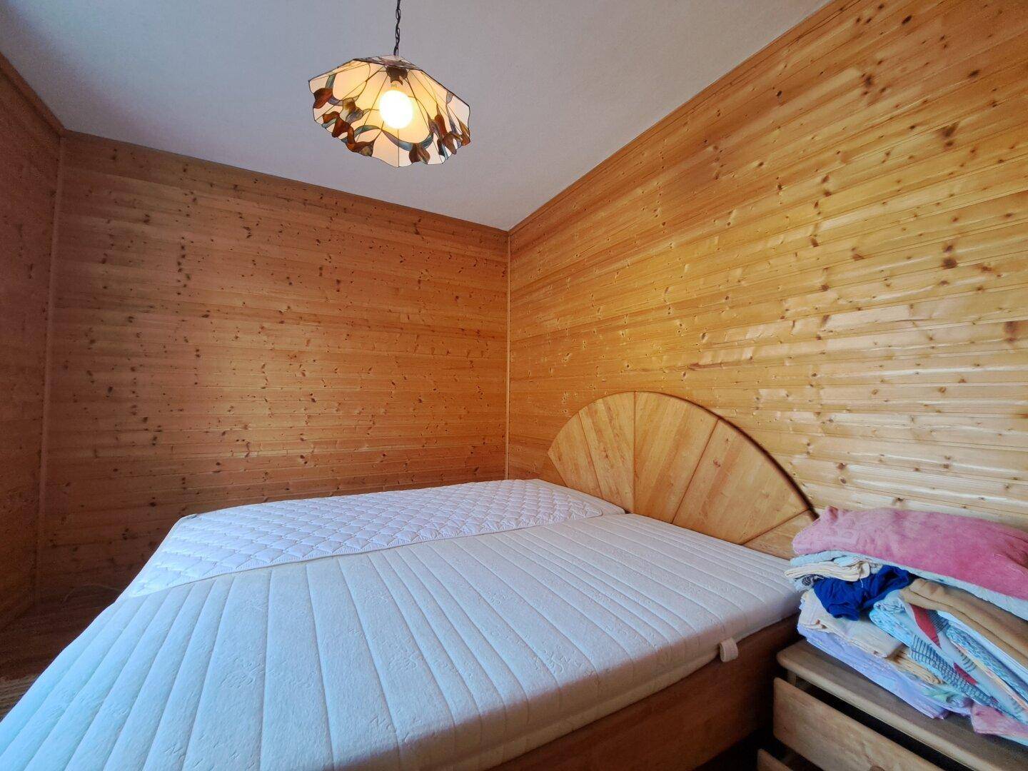Schlafzimmer mit Holztäfelung an den Wänden und einem Doppelbett.