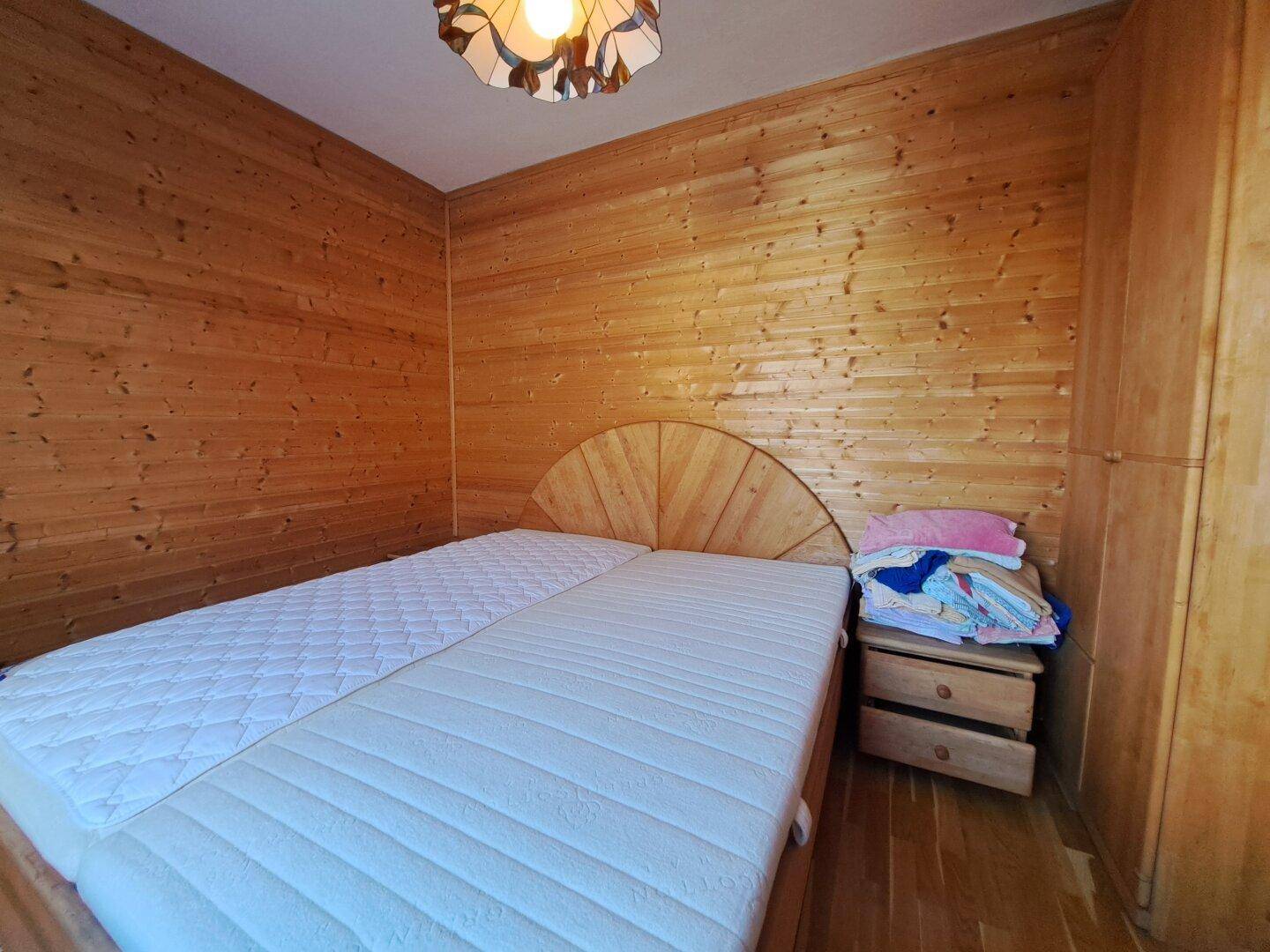 Gemütliches Schlafzimmer mit durchgehender Holzverkleidung und Holzboden.