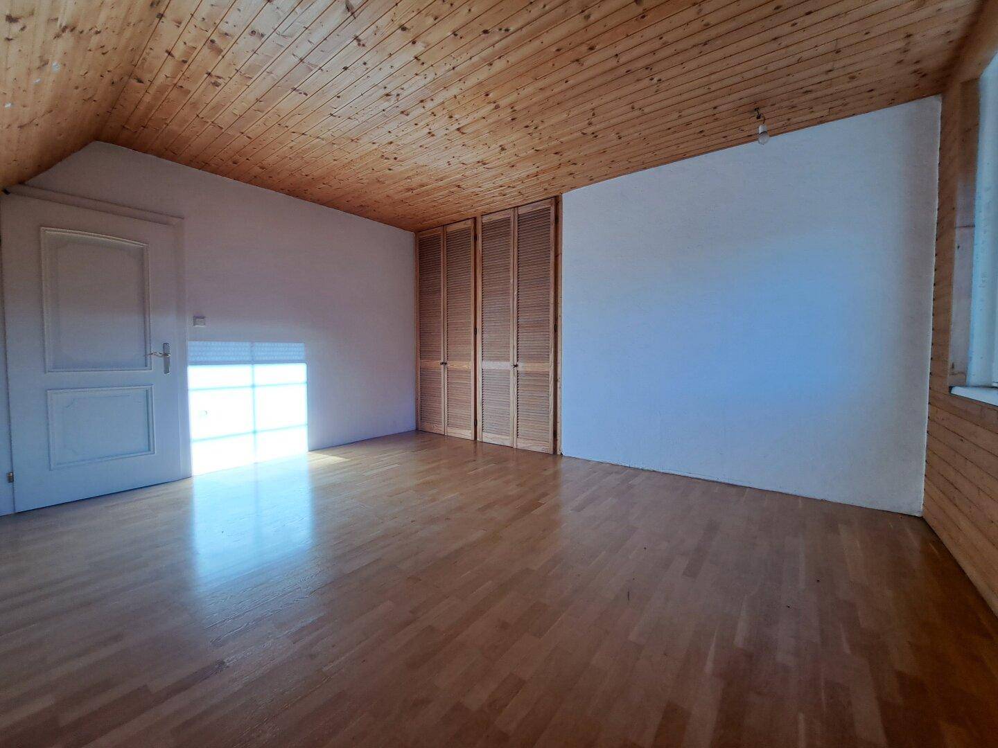 Dachbodenraum mit Holzboden, schräger Decke und Einbauschränken.