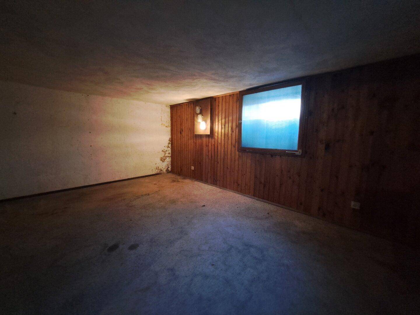 Kellerraum mit Holzverkleidung, Betonboden und Renovierungsbedarf.
