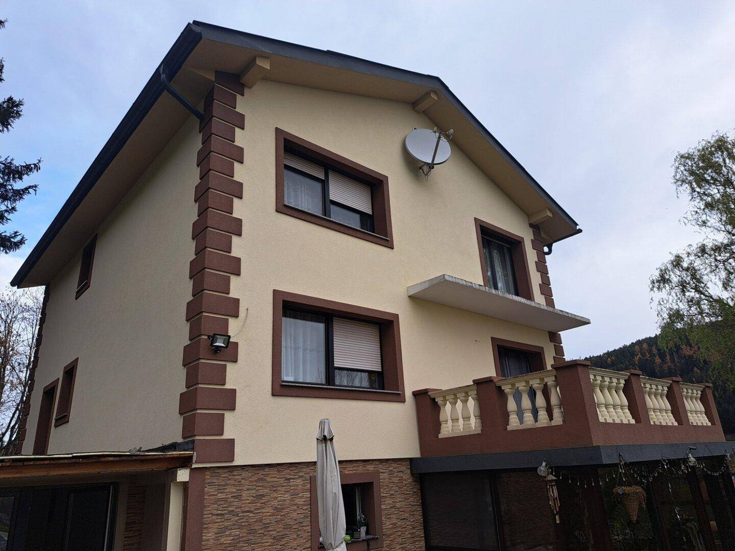 Hausfassade mit einem Balkon im ersten Stock, Rollläden und traditionellen Verzierungen.