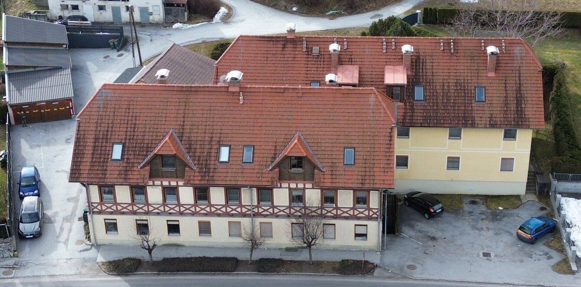Übersicht des Anwesens mit traditioneller Architektur, roten Dächern und umliegenden Grünflächen.
