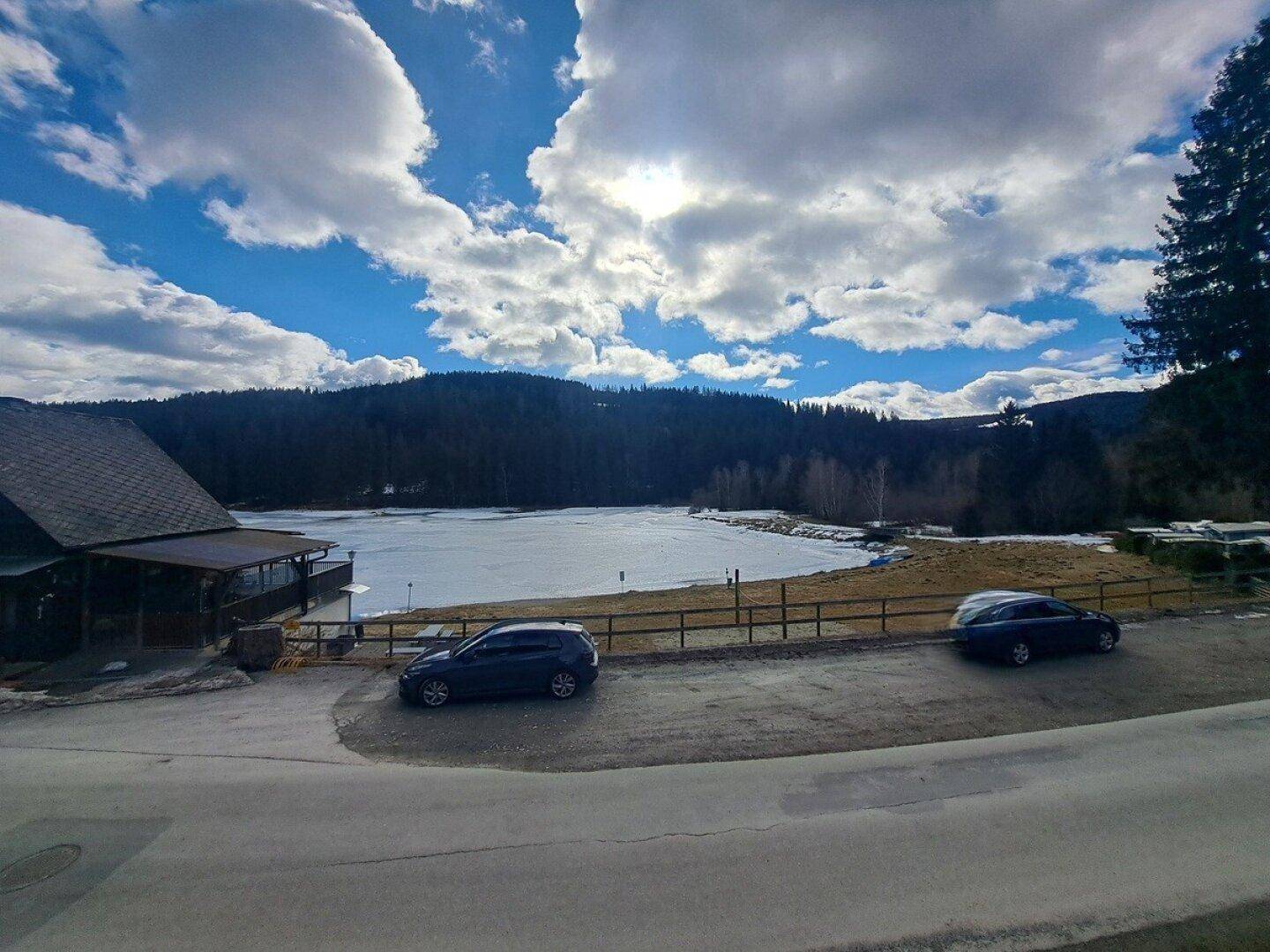 Malerischer Blick auf einen zugefrorenen See umgeben von Wäldern und Bergen.
