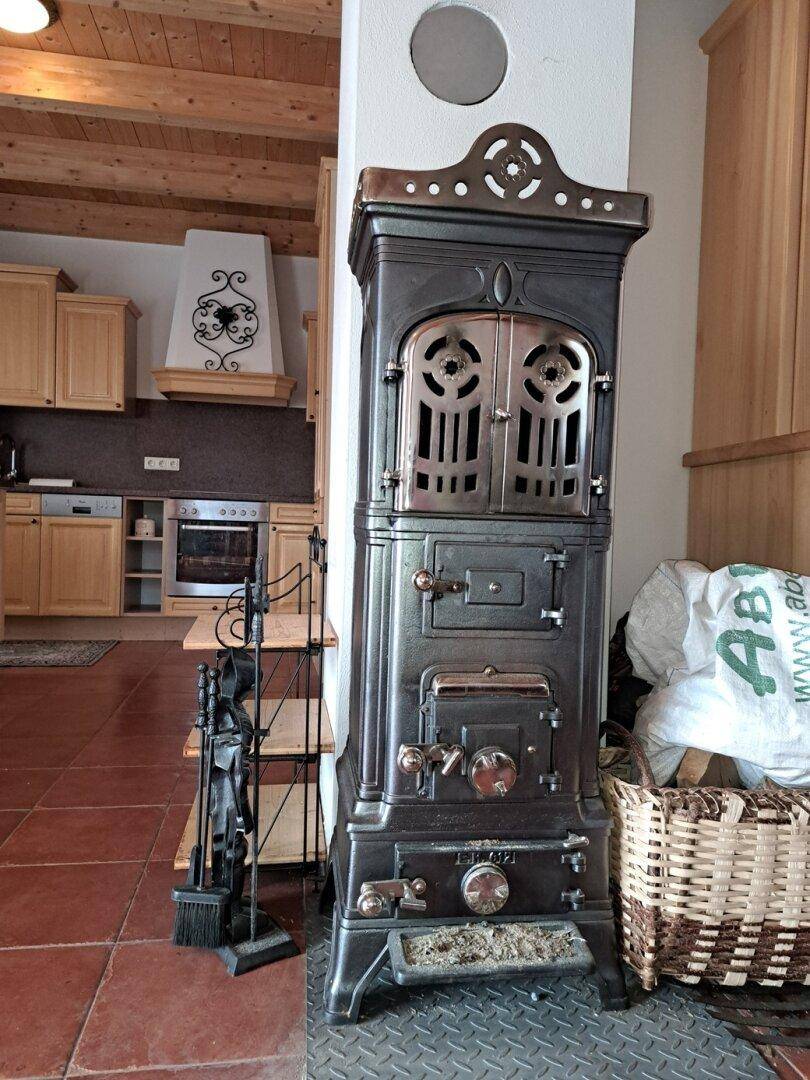 Detailansicht eines traditionellen Kaminofens in der rustikalen Küche mit Holzelementen.