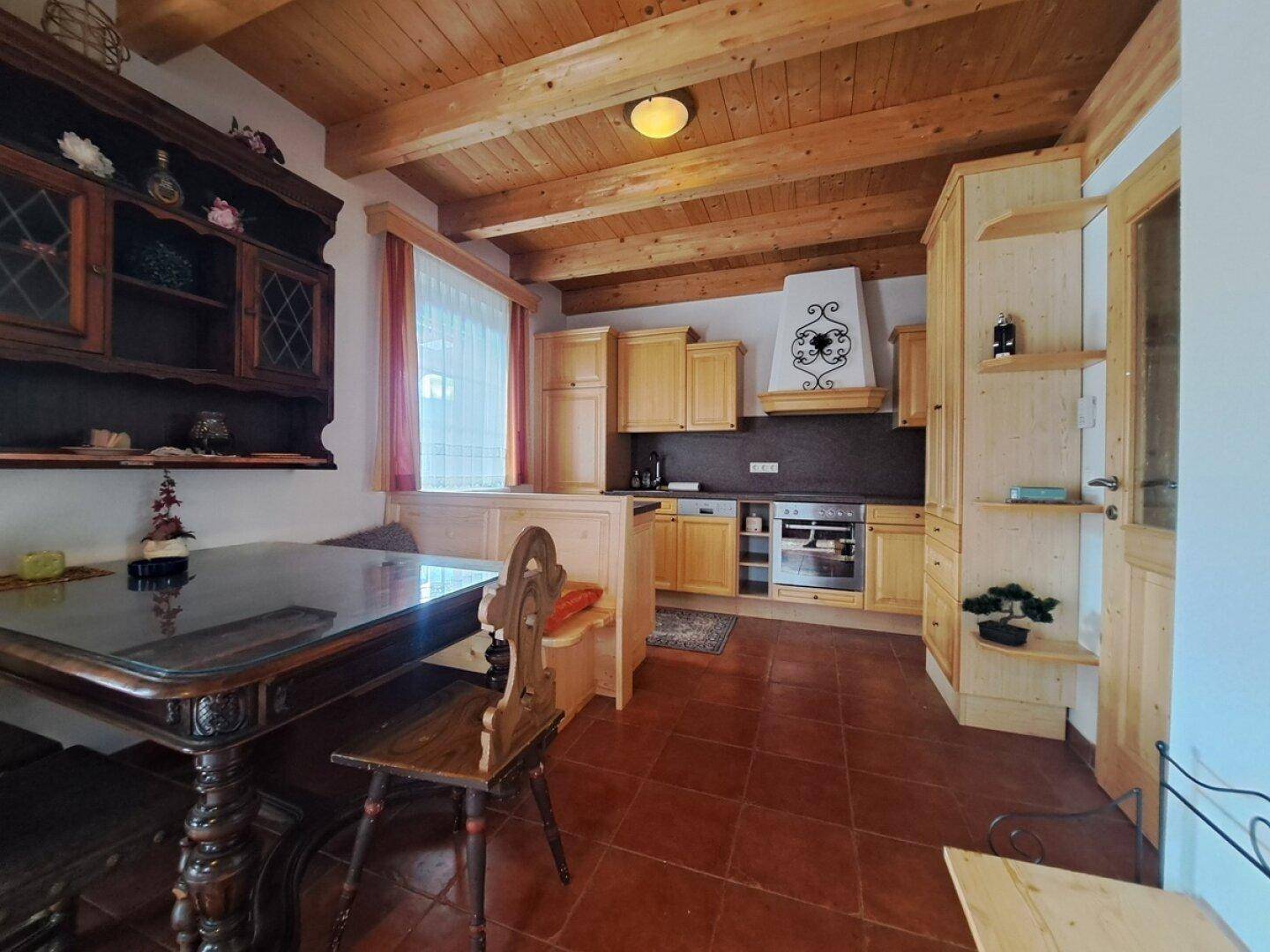 Rustikale Wohnküche mit Holzeinbauten, Esstisch und traditionellem Geschirrschrank.