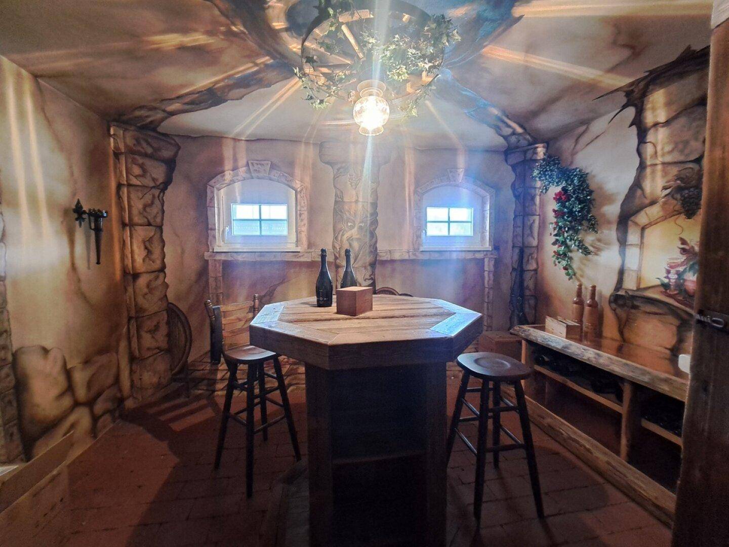 Gemütlicher Weinkeller mit rustikalem Holztisch und kleinen Fenstern.