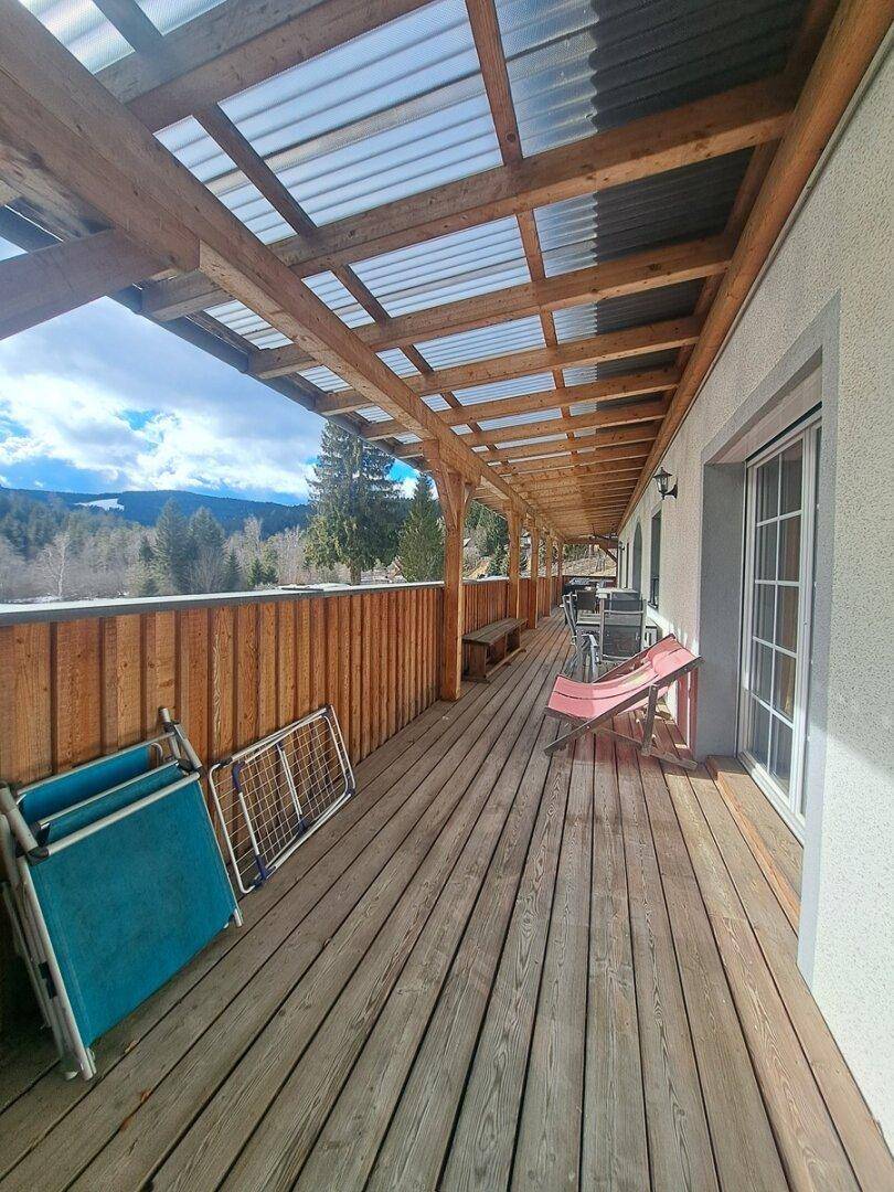 Überdachte Holzterrasse mit Sitzgelegenheiten und weitem Blick in die Landschaft.